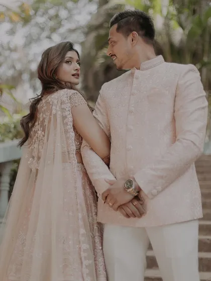 A romantic over-the-shoulder glance from the bride, dressed in an elegant pastel lehenga with a cape.