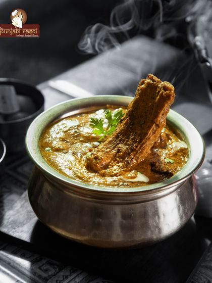 Heavenly. This moody shot captures the essence of our rich mutton curry, steaming hot and ready to be savored. A true taste of authentic Punjabi cooking.