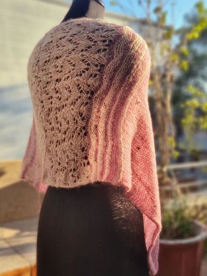The back of this shrug features a beautiful, intricate lace knitting pattern. It adds a surprising and delicate detail to the piece.