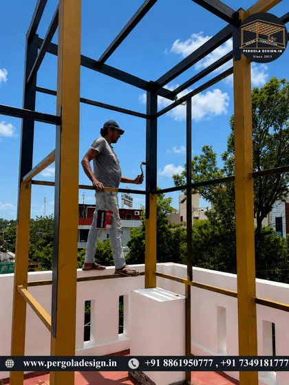A worker applies a coat of paint to the pergola frame, a crucial step in our weatherproofing and finishing process.