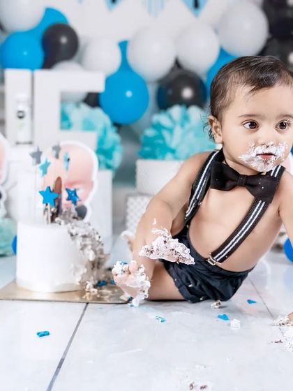 The cake smash is underway! A baby boy crawls through the frosting, leaving a trail of mess and fun behind him.