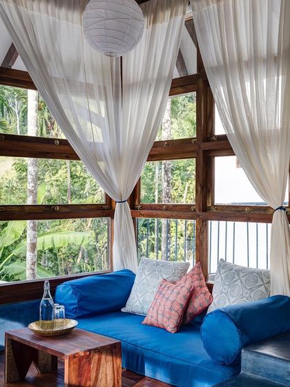 A cozy seating nook in the Sky Room, surrounded by windows that look out into the tree canopy. It's a perfect spot for reading or simply enjoying the view.