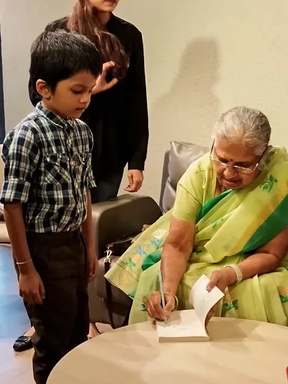 A young boy patiently waits as Sudha Murty signs his book. Getting a book personally signed by an author is a magical experience that we love to facilitate for our members.