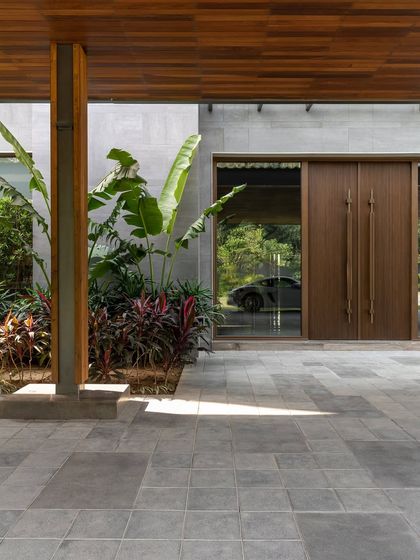 The entrance of the K Residence, where a glass facade offers a glimpse of a luxury car, reflecting the client's passions. The design thoughtfully integrates personal elements into the architectural narrative.