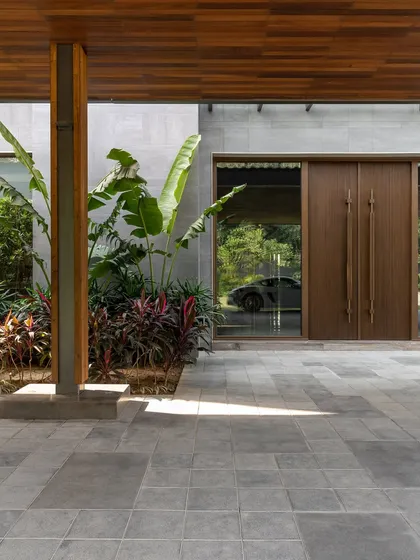 The entrance of the K Residence, where a glass facade offers a glimpse of a luxury car, reflecting the client's passions. The design thoughtfully integrates personal elements into the architectural narrative.