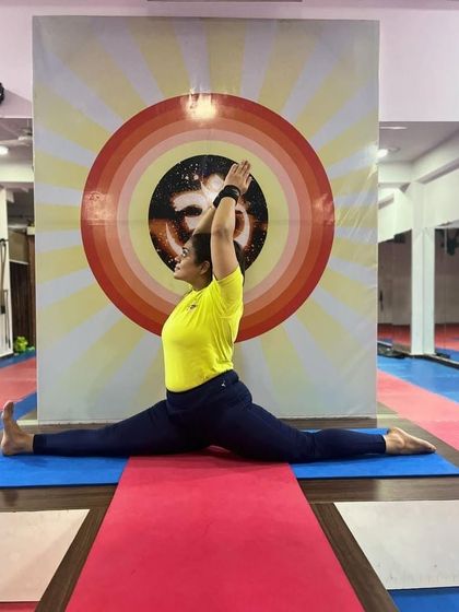 A student demonstrates a deep Hanumanasana (Full Split), showcasing advanced flexibility in the hamstrings and hips.
