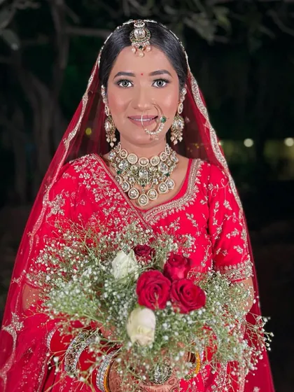 A beautiful bride in red, holding a bouquet of roses. Her makeup is soft and elegant, perfect for a classic wedding look.