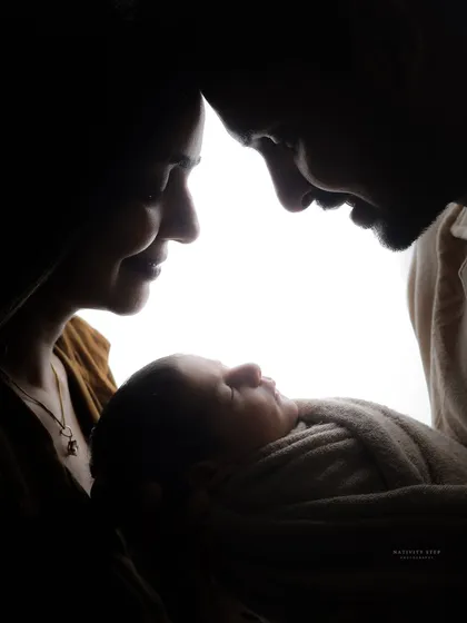 A beautiful rim-lit portrait of a family admiring their newborn. This black and white photograph has a timeless, classic feel that emphasizes emotion and connection.