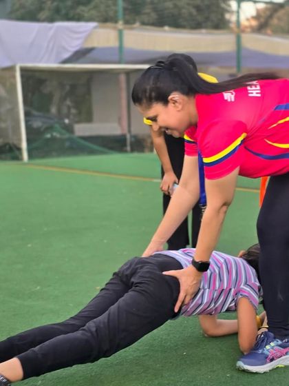 Even a simple plank becomes a fun challenge with friends. A coach helps a child maintain correct form during a birthday party game, blending fitness fundamentals with celebratory fun.