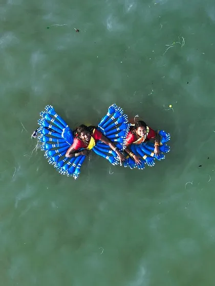 This top-down drone photo captures two performers during the Kulasai Dasara festival in Tamil Nadu. The vibrant blue costumes create a stunning butterfly-like shape on the surface of the water, showcasing the festival's unique and colorful traditions.