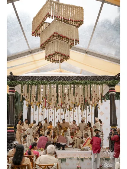 The wedding ceremony in progress under a magnificent floral chandelier and a canopy of hanging garlands. The scale of the decor creates a truly opulent and memorable setting.