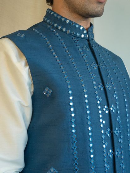 The geometric patterns created with mirror work offer a contemporary flair to this traditional Nehru jacket, making it a versatile piece.