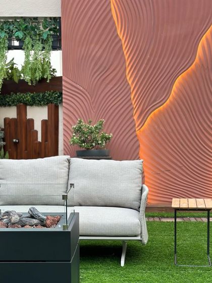 A close-up of the terrace seating area, featuring a modern sofa next to a firepit and a sculptural, illuminated wall. This composition shows our attention to detail in creating functional art within a landscape.