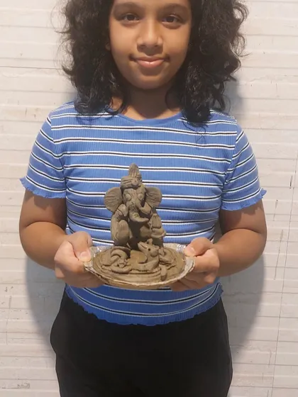 A young girl with her finished clay Ganesha. The joy of creating something with her own hands for the festival is a memory she will cherish.