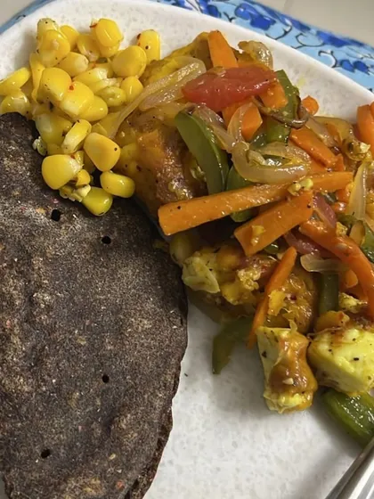 A balanced meal of paneer and vegetable stir-fry served with a ragi (finger millet) roti and a side of corn. This combination provides protein, fiber, and complex carbs.