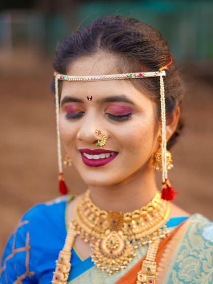 A detailed close-up focusing on the bride's expressive eyes and flawless makeup. This shot highlights the artistry of the bridal look, from the colorful eyeshadow to the delicate bindi.