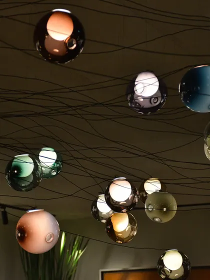 A close-up of the multi-colored Bocci 28 pendants. The intricate wiring is part of the design, creating a deliberate and artistic tangle that connects the individual spheres.