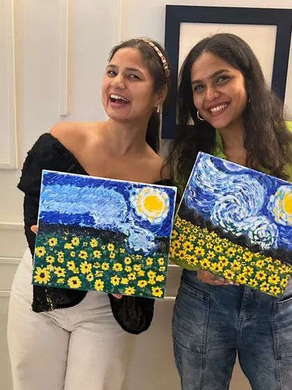 Two friends celebrating their artistic success with their matching 'Starry Night' inspired paintings.