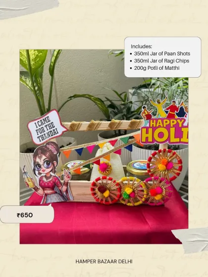 The Festive Delight Hamper for Holi, priced at ₹650. This one comes in a decorated wooden cart and contains jars of paan shots and ragi chips, plus a potli of matthi.
