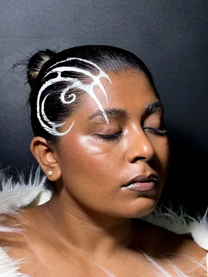 This look was a fun challenge: creating a graphic liner pattern directly on the hair. I used a white aqua color to paint a swirling, tribal-inspired design, keeping the face makeup minimal and dewy.