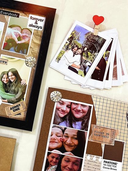A detailed shot of my scrapbook-style gifts. You can see the layers of photos, stickers like "Admit One," and a stack of polaroids held together with a tiny heart clip.