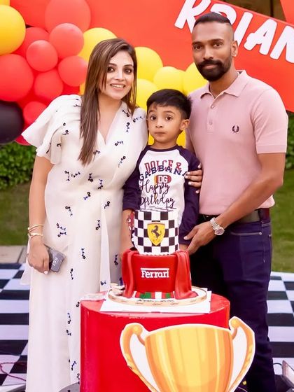 A happy family photo from Krianshh's Ferrari-themed birthday party, posing with the race car cake.