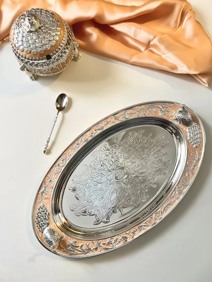 With every detail thoughtfully designed, this peach enamel tray and matching dry fruit box set is perfect for serving, gifting, or simply admiring. The intricate silver work adds a layer of luxury.