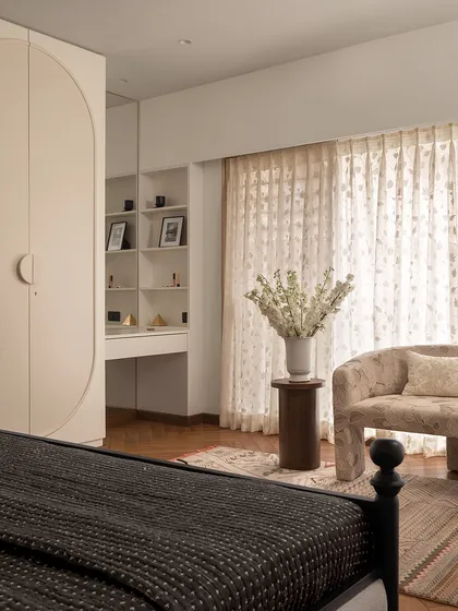 The master bedroom in "Apartment 222" features a custom wardrobe with sleek, curved doors and an integrated dressing table. The design maximizes functionality while maintaining a clean and elegant look.