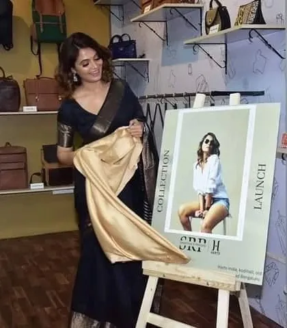 A candid moment of Shwetha Prasad at a launch event, looking chic and elegant in our black Maheshwari saree.