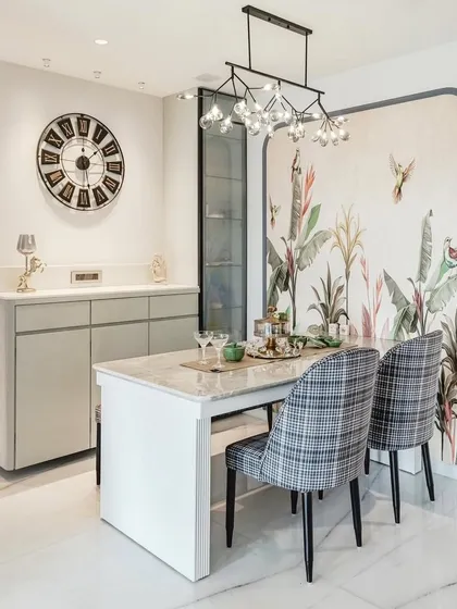 We transformed this dining area into an elegant space for meals and gatherings. The design is centered around a marble-top table and features a custom tropical wallpaper for a touch of artistry, a modern chandelier for dramatic lighting, and a sleek crockery unit for practical storage.