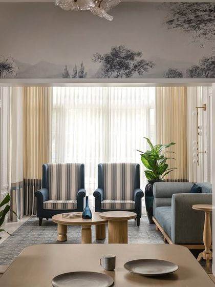 A view from the dining room into the sunroom, framed by walls covered in a beautiful black and white toile wallpaper. This layering of spaces creates depth and a continuous design narrative throughout the home.