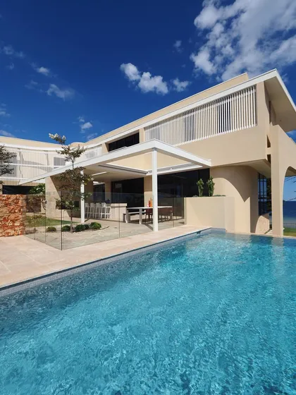 A wide view of a modern coastal home where the pool and patio are the main features. The design is open and spacious, taking full advantage of the seaside location and sunny climate.
