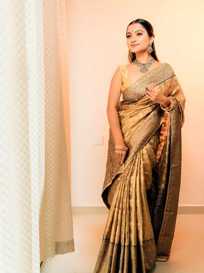 A full-length shot of the model in the golden saree, showing its beautiful sheen and drape.