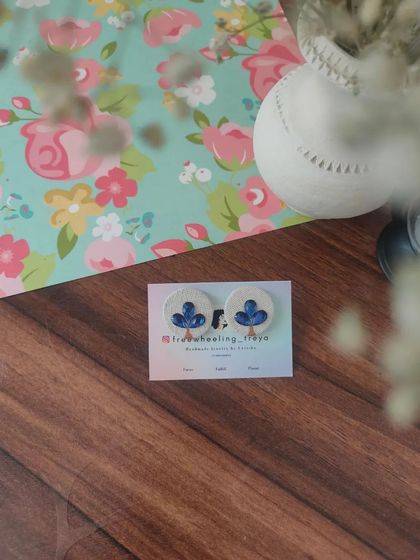 A collection of my simple and elegant fabric studs. Each pair is hand-painted with a small leaf motif and comes in a variety of colors like green, white, yellow, blue, and pink.