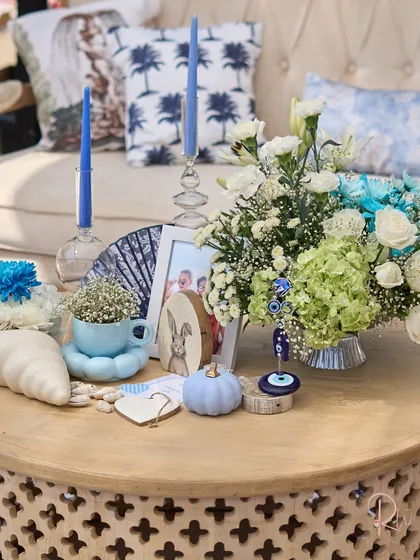 A detailed shot of the table decor, including a baby's breath arrangement in a teacup, a pastel blue pumpkin, and an evil eye charm.