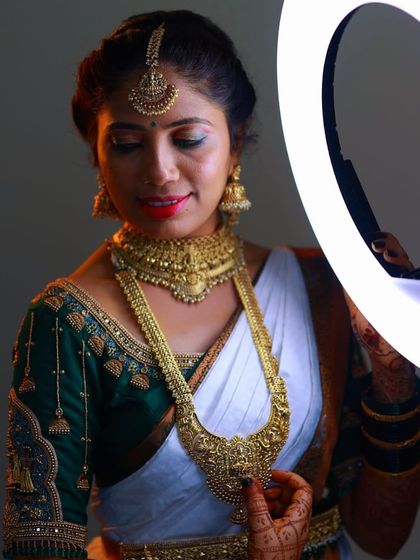 A moment of quiet beauty before the ceremony. Our client Mamatha looks elegant in a traditional gold temple necklace set, featuring a detailed choker and a matching long haram that perfectly complements her white and green saree.