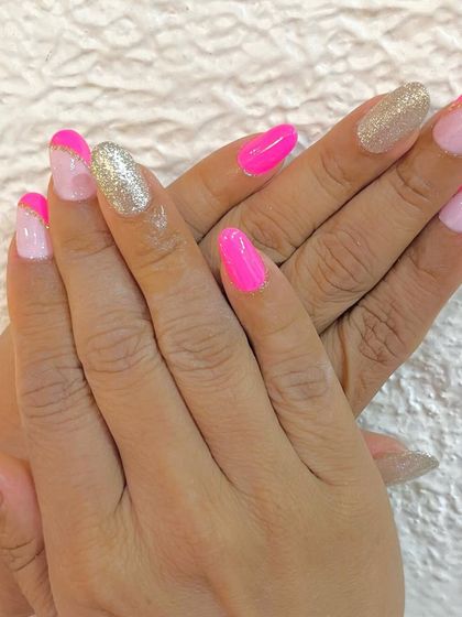 Hot pink nails with a swirl of glitter. This fun set combines solid pink nails, glittery gold nails, and French tips with a pink and gold glitter line.