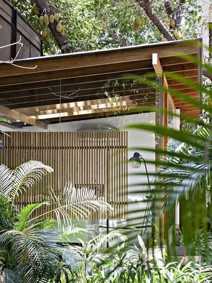A pavilion space in Mumbai that feels completely immersed in tropical greenery. By using glass walls and slatted screens, we created an indoor space that feels like it's part of the outdoors.