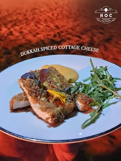 Our Dukkah Spiced Cottage Cheese, plated here for an evening event. The warm lighting highlights the crispy texture of the spiced crust and the fresh arugula garnish.