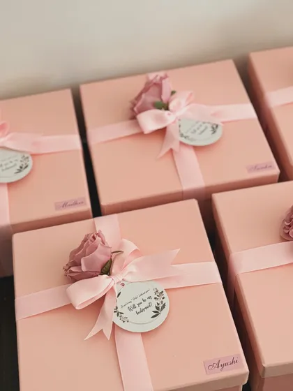 The final touch on our bridesmaid proposal boxes. Each pink box is tied with a ribbon and a custom tag asking, "Will you be my bridesmaid?", making the moment truly special.