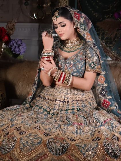 A stunning bridal portrait in a multi-colored, intricately embroidered lehenga. The makeup is a classic smokey eye with a nude lip.