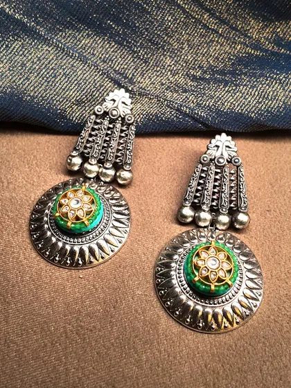 Classics that never fade. These oxidized silver earrings feature a disc design with a central floral motif in turquoise and polki, perfect for a rustic-chic look.