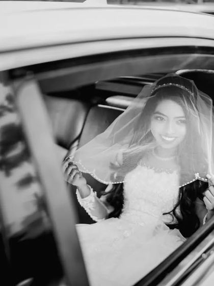 The bride looking up with a bright smile from the wedding car. This black and white shot captures the excitement and anticipation of the moment.