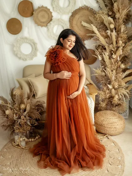 A solo portrait is a powerful way to celebrate your strength and beauty during pregnancy. This mom-to-be is glowing in a gorgeous rust-colored gown, set against a rustic, earthy backdrop that feels both warm and stylish.