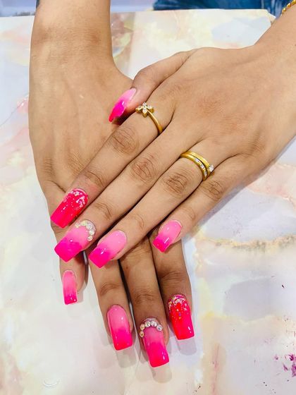 A vibrant pink ombre set on long coffin nails, adorned with delicate floral painting and rhinestone clusters.