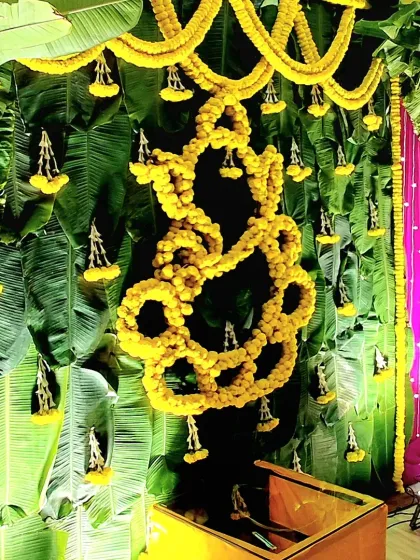 A Ganesha motif skillfully crafted from yellow marigolds against a backdrop of banana leaves, a traditional and auspicious decor piece for a Diwali celebration.