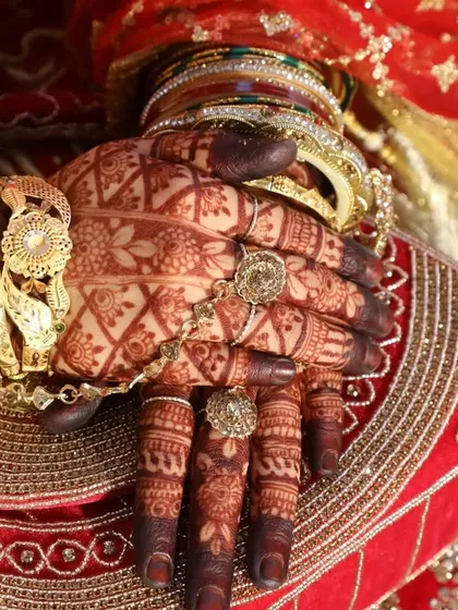 Another angle of this stunning bridal henna, showing how the dark stain complements the intricate gold jewelry and traditional red wedding attire.