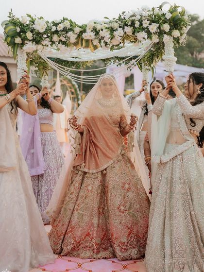 The bride's entry at her outdoor wedding in Khandala. The floral 'phoolon ki chadar' and the open-air setting create a beautiful, natural, and joyous moment.