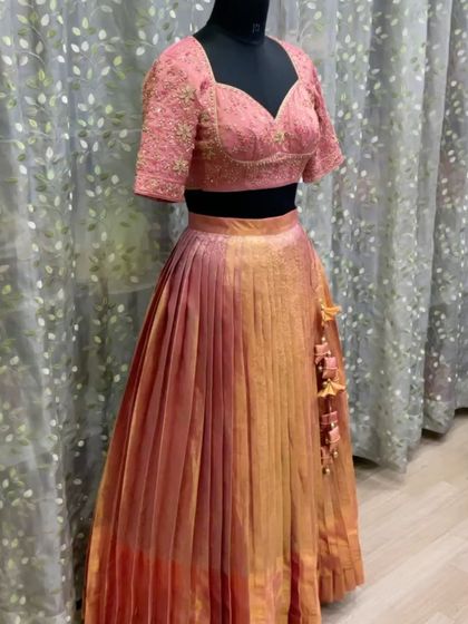 A full view of the peach and gold langa davani on a mannequin. The blouse has a sweetheart neckline and embroidered sleeves, and the skirt has beautiful custom tassels.