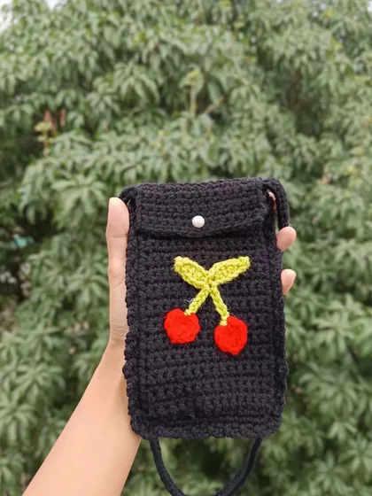 A black phone sling with a cute cherry applique. The simple button closure is both practical and stylish.